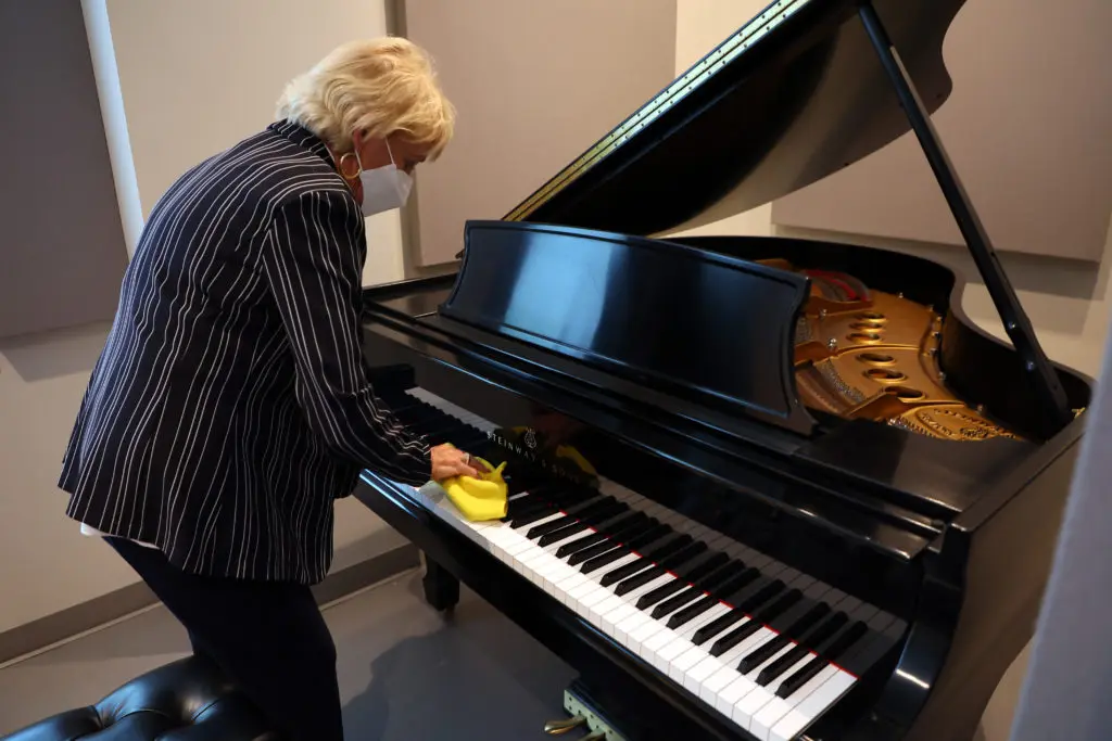 Backstage mom Katie Cummins wipes down the piano in the competitor's dressing room. (Photo by Richard Rodriguez)