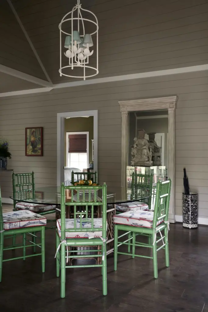 In a dining area, wicker and bamboo table from 1stDibs. Chinoiserie-inspired chairs from Memorial Antiques & Interiors, Houston. Visual Comfort light fixture. Black-and- white ceramic umbrella stands were handmade in Dolores Hidalgo, Mexico. Chinese scholar sculpture is antique and was purchased in Paris by Fourticq decades ago. (Photo by Pär Bengtsson)