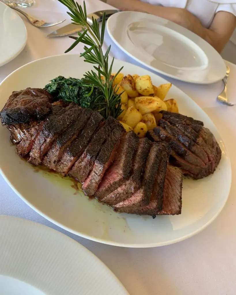 Amore's Bistecca alla Fiorentina is a simply seasoned and grilled porterhouse cut that arrives sliced off the bone with the filet separated from the strip, sautéed garlic-tinged spinach and roasted Yukon Gold potatoes by its side.  (Photo by Laurann Claridge)