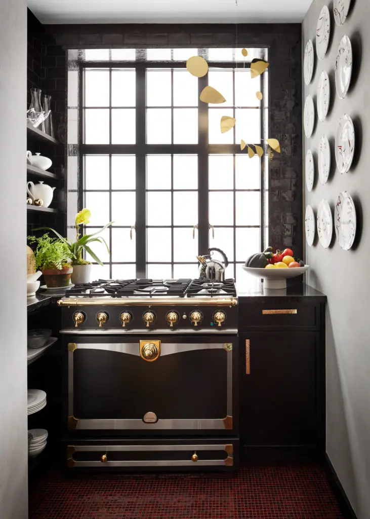  In Caleb Anderson’s New York apartment, the kitchen is a wonderful room in which to cook when time permits. A little garden grows to the left; to the right, a series of plates hand-painted with abstract faces animates the wall. The mobile might be impractical, but it inserts a playful note. (Photo by Stephen Kent Johnson)