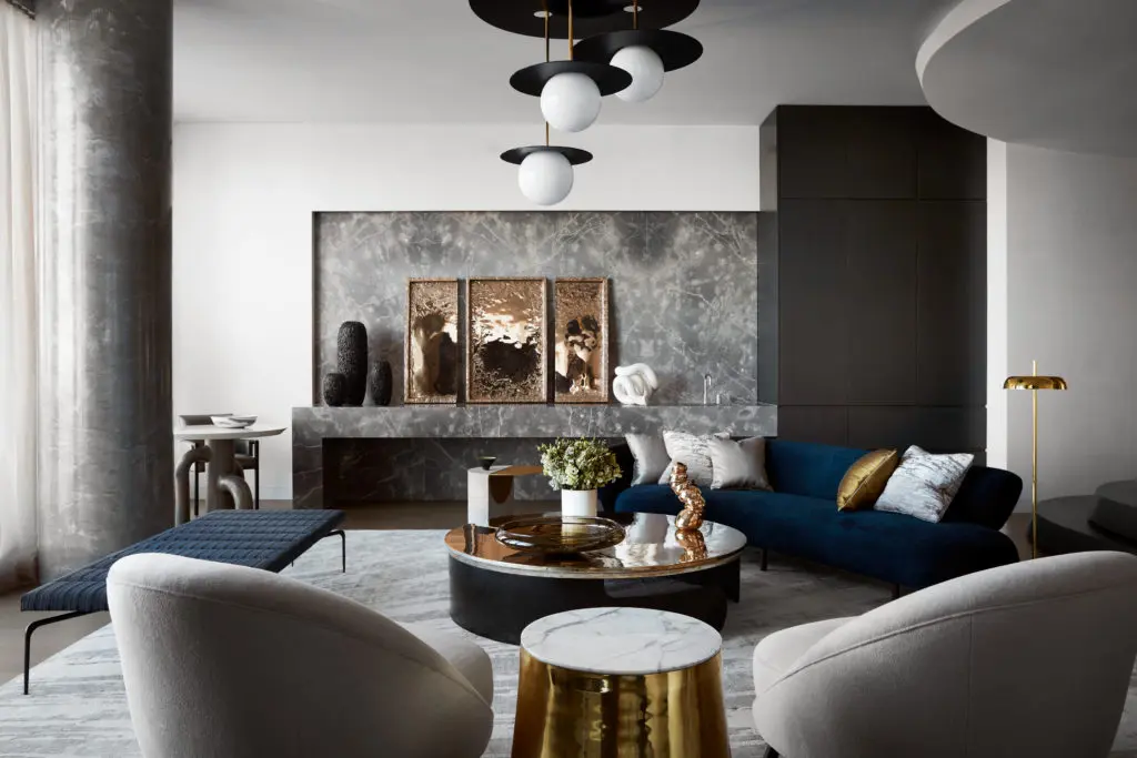 The sensuous furniture in this full-floor Tribeca aerie designed by Drake/Anderson reiterates recurring motifs. On the back wall, a gray stone inset and counter incorporate a wet bar. (Photo by Stephen Kent Johnson)