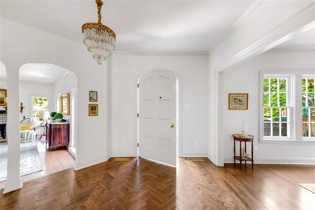 A welcoming, wedding cake chandelier and gleaming herringbone wood floors greet you in the foyer.
