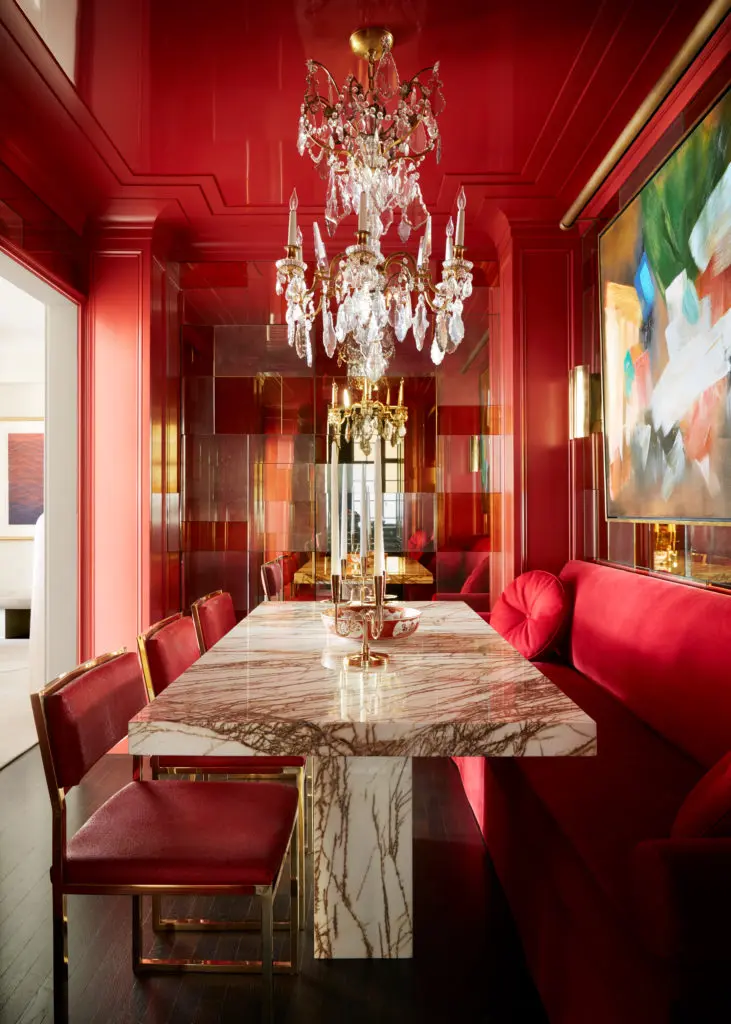 The dining room in Caleb Anderson's prewar New York apartment features a custom dining table made from a slab of Golden Spider marble. The 1920s Baccarat chandelier twinkles above Tommi Parzinger candelabras. The chairs are by Milo Baughman. (Photo by Stephen Kent Johnson)