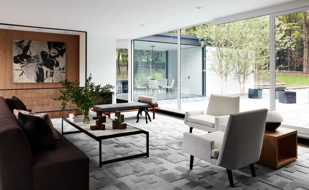 In this project designed by Drake/Anderson the living-room furnishings address each other and the fireplace in this ode to the iconic glass houses of Ludwig Mies van der Rohe and Philip Johnson, situated among hundreds of acres of woods in New York State’s Columbia County. (Photo by Stephen Kent Johnson)