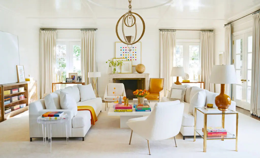 Kasler painted her family room glossy white to make everything look fresh. The sculptural chandelier and new Damien Hirst work over the fireplace set the tone. (Photo by Melanie Acevedo)