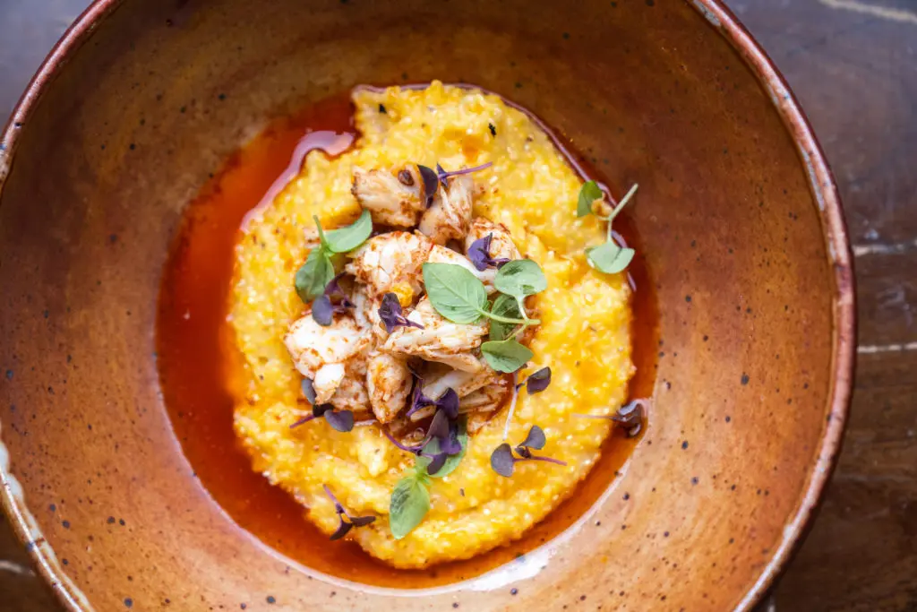 Chef Andre Garza's unctuous brunch dish, heirloom grits, are seasoned with chili laced garlic butter and topped with jumbo lump crabmeat.  (Photo by Michael Anthony)