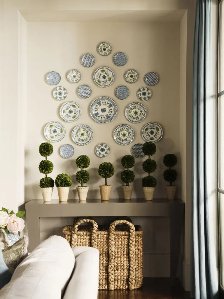 The homeowner's collection of china plates serve as a gallery wall accented by the collection of boxwood topiaries atop a console table.  (Photo by Jack Thompson)