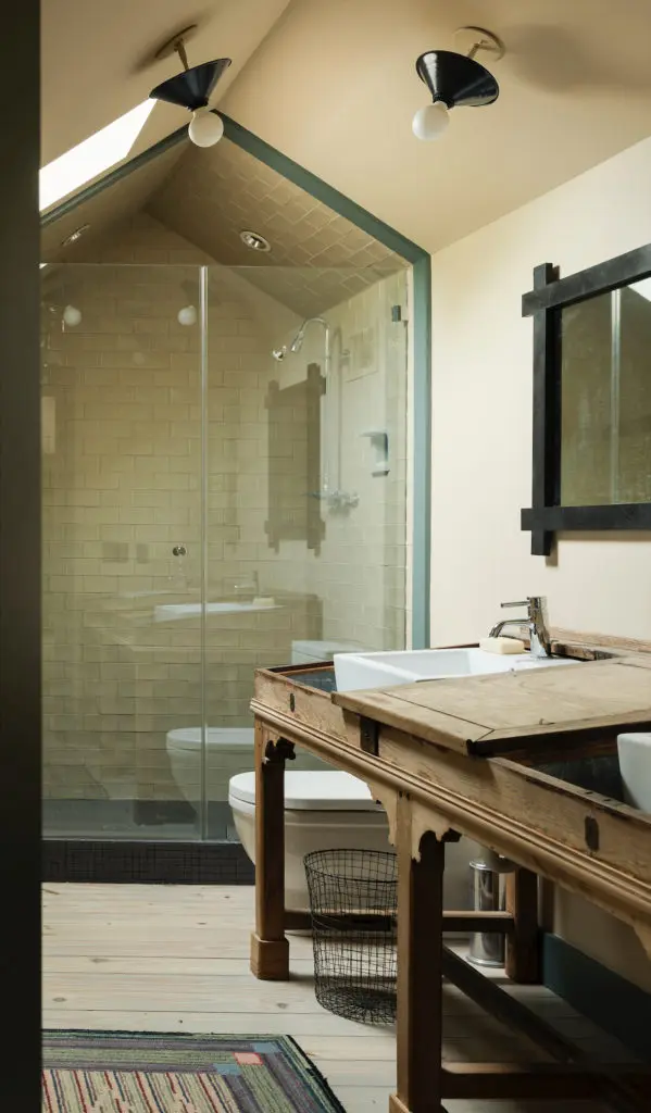  In the upstairs bath, a reclaimed-pine console holds a pair of sinks. Unstained pine-wood floors give an aged look.
 (Photo by Jack Thompson)