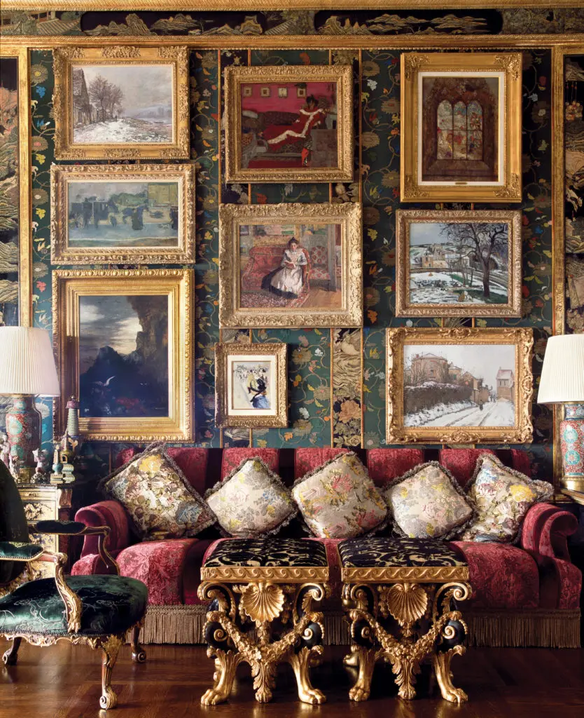 A large-scale, velvet-upholstered sofa anchors the living room, with seating for eight or more. Paintings include a Gustave Moreau, a petite Renoir portrait, and a Camille Pissarro snowy landscape. The empty space on the Chinese gauze–covered wall is usually filled by an 1888 painting of St. Martin-in-the-Fields by William Logsdail, which was on loan for a museum exhibition. The pair of carved parcel giltwood and ebonized stools, upholstered with Bevilacqua silk velvet, is George II , circa 1740. (Photography by Lisa Romerein)