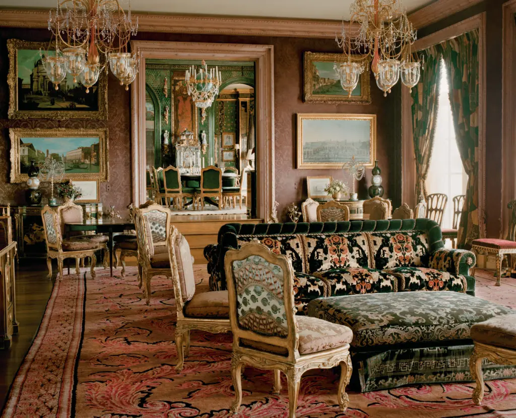 The music room, adjacent to the dining room, has a Russian theme that resonates with the English country overview of the house. The hand-knotted wool rug is Russian, formerly in the collection of the Scottish Duke of Hamilton, who used it when he took over the Queen's Apartments at the Palace of Holy Roodhouse in Edinburgh in 1684. Patchwork curtains from the estate sale of dancer Rudolf Nureyev's Paris apartment. (Photography by Lisa Romerein)