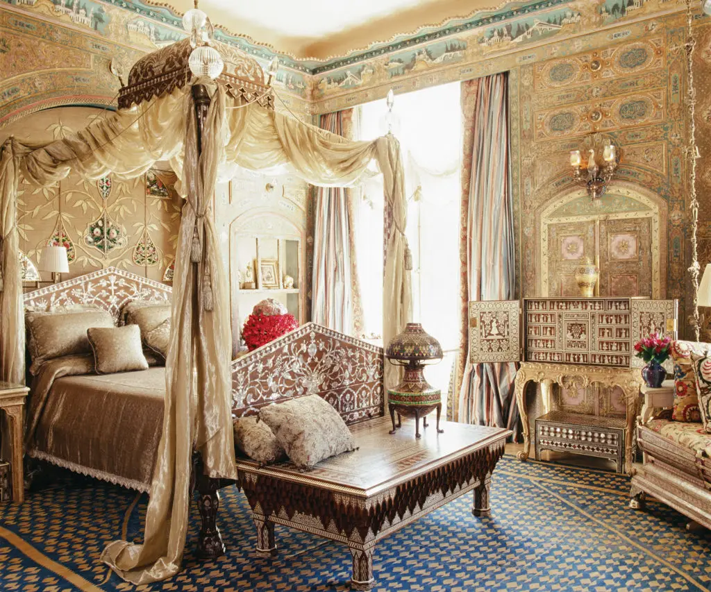 The design of the opulent mother-of-pearl and wood-inlaid bed is based on a throne at Topkapi palace in Istanbul. The headboard is decorated with 10 very rare Qajar mirror paintings (verre églomisé) depicting delicate flowers, birds, and leaves. The 19th-century sandalwood table, foreground, is Egyptian. A late-17th-century Indian ivory and sheesham wood cabinet, right, balances on a George I cabriole-leg fruitwood stand. Apainting by Eugene Delacroix of a Moorish tribal chief, paintings by Jean-Léon Gérôme, Henri Matisse drawings of his model in Moroccan costumes, Anglo-Indian 18th-century engraved ivory side chairs, and exquisite embroidered textiles are deployed throughout the suite. On the floor of the bedroom is a rare Bessarabian tapestry-woven carpet, circa 1890. (Photography by Lisa Romerein)
