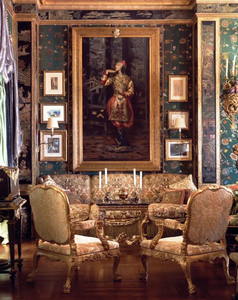 The living room shimmers with hand-woven silk, jade collections, woodcarving, antique textiles, and the glow of gold. The pair of early-eighteenth-century giltwood armchairs was designed by John Vardy for Spencer House, London. The portrait of Nijinsky in a Ballets Russes Siamese costume was painted circa 1910 by Jacques-Emile Blanche. The costume was designed by Leon Bakst. (Photography by Lisa Romerein)
