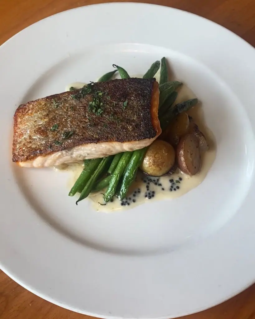 A recent salmon dish from sister restaurant Clay Pigeon featuring green beans, marble potatoes, Cipollini onions, and a decadent caviar beurre blanc.