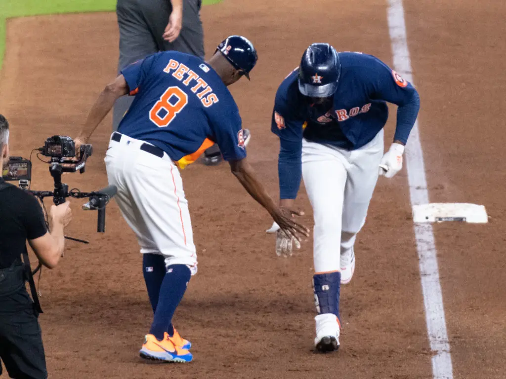Houston Astros star Yordan Alvarez gives third base coach Gary Pettis a low five. (Photo by F. Carter Smith)