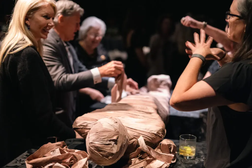 Members of the HMNS Curator's Circle assist in unwrapping a replica mummy.(Photo by Mike Rathke)