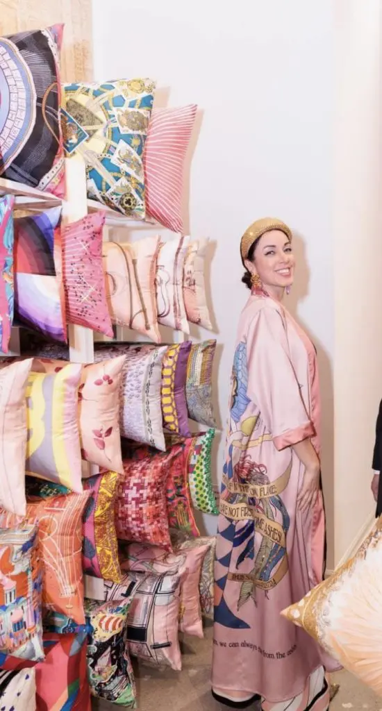 Sandra Serrani with Tribute Goods pillows on dislay at the Arsin Rug Gallery one year anniversary celebration in Decorative Center Houston. 