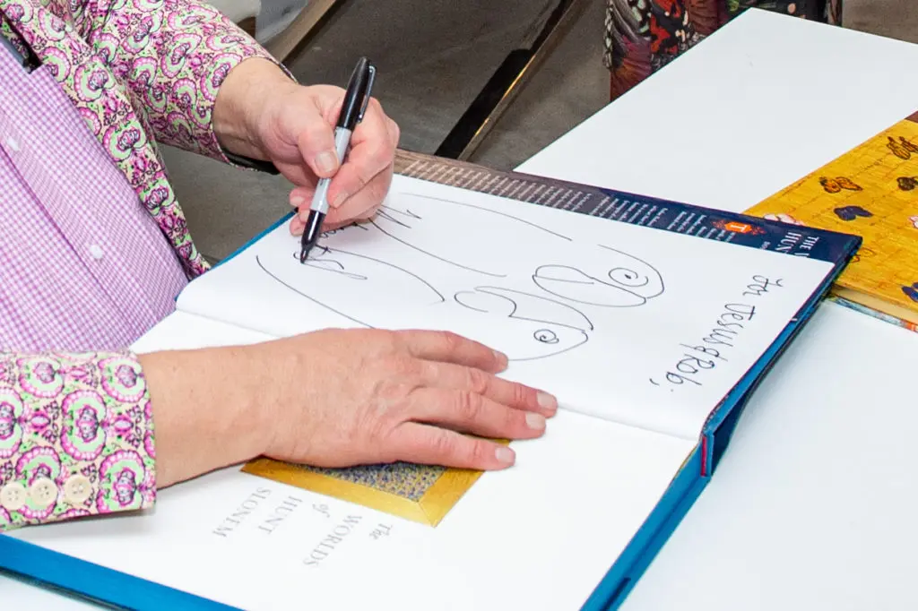 Hunt Slonem signs a volume with a bird drawing at Laura Rathe Fine Art opening for Year of the Rabbit (Photo by Jacob Power Photography)