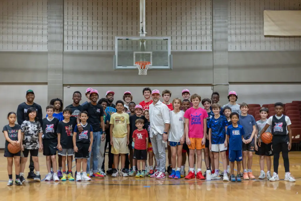 UH point guard Jamal Shead and New Leaf founder David Houston posed with all the kids. (Courtesy New Leaf real estate)