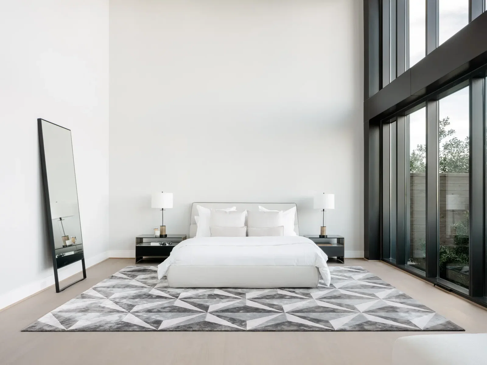The main floor primary bedroom of the CASA Companies' condo enjoys two stories high windows facing north. (Photo by Divya Pande)