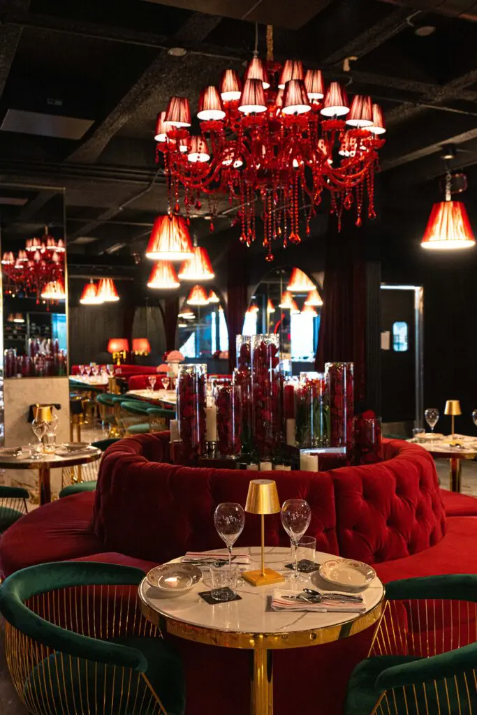 Here in the 6,600 square foot space (with 220 seats) designed by architect Adel Sadek diners are cosseted in plush, curvaceous rosy velvet booths, and golden Platner-style chairs, dimly lit from above with merlot-colored silk-shaded lights and chandeliers dripping with crystal-like bibelots. (Photo by Michael Anthony)