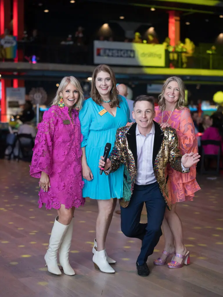 Victory Rally Ball chairs Elizabeth Fulghum, Stephanie Morris, Melissa Hobbs with auctioneer Johnny Bravo (Photo by Daniel Ortiz)