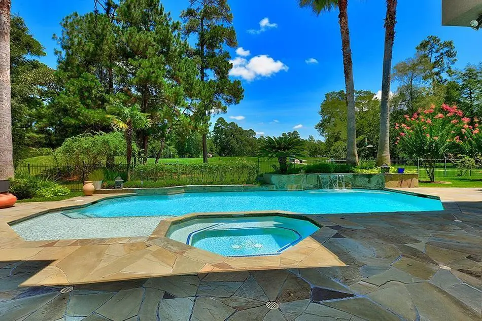 Watch over the Palmer Golf Course from your backyard at 30 Cape Jasmine Place. This Woodlands pool comes with a view.