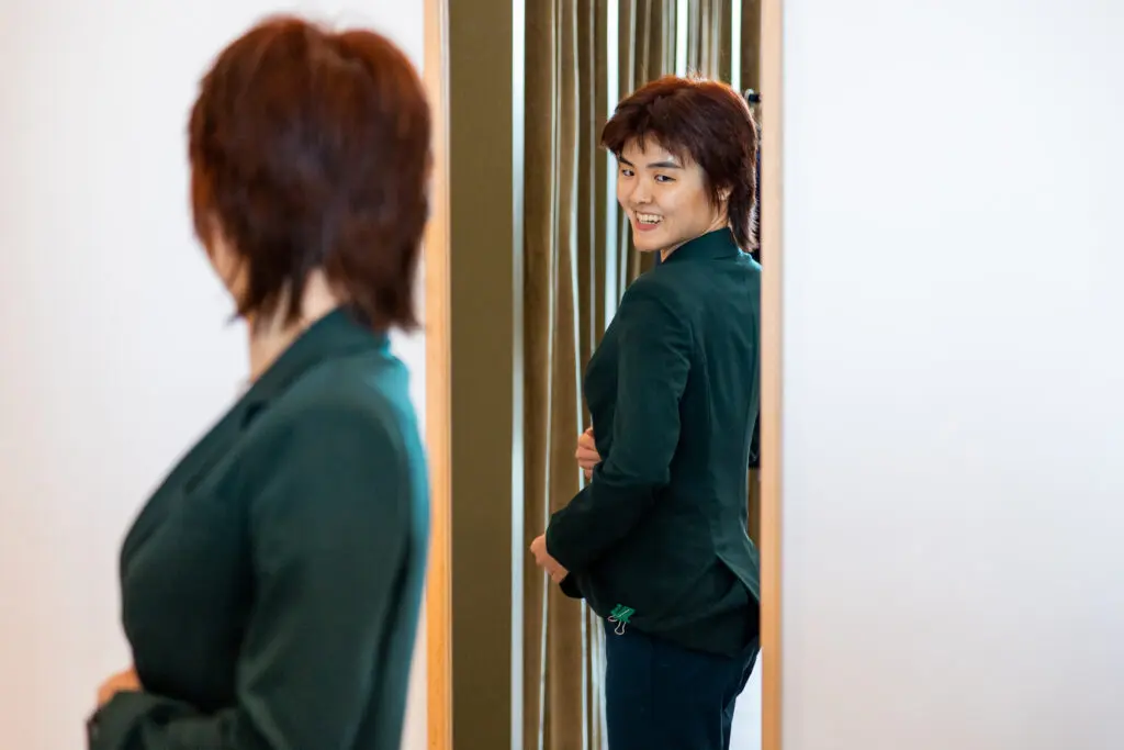 Caitlin Hsu examines a dark green suit in the mirror at Suit Shop. (Photo by Adam Hart)