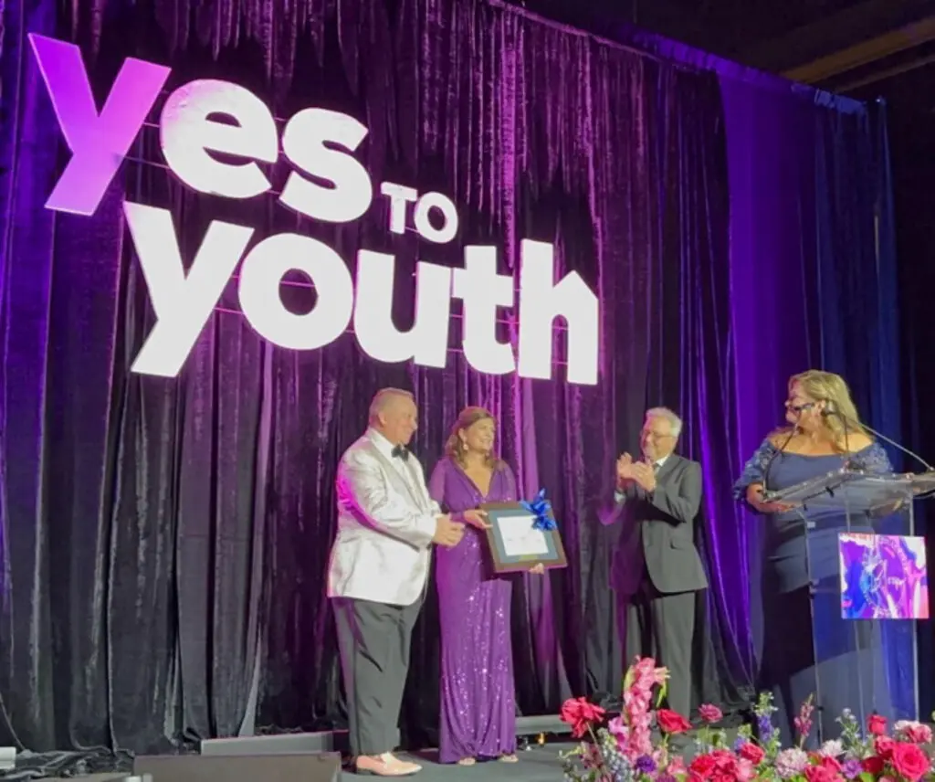 YES to YOUTH Board Chair, Bill Malone presents a watercolor painting of the BridgeWay Youth Shelter to Kristin L. Young, honoree.  Fellow honoree, Dan Kolkhorst, YES to YOUTH Board member represents Honoree Howard Hughes as Corporate Honoree. Michele Kooken, YES to YOUTH CEO, expresses her thanks for their exemplary service to YES to YOUTH.