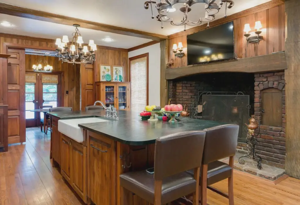A unique Dilbeck kitchen with black soapstone counters and an oversized brick fireplace.
