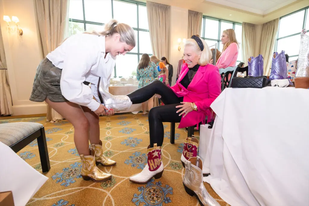 Trying on Miron Crosby boots at the 2023 Desert Rose Luncheon. (Photo by Sharon Ellman)