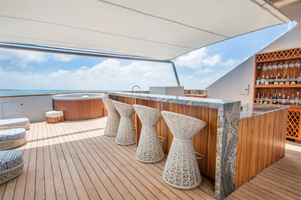 The top deck is partially shaded and fashioned with day beds, hammocks, an outdoor shower, and wet bar. 