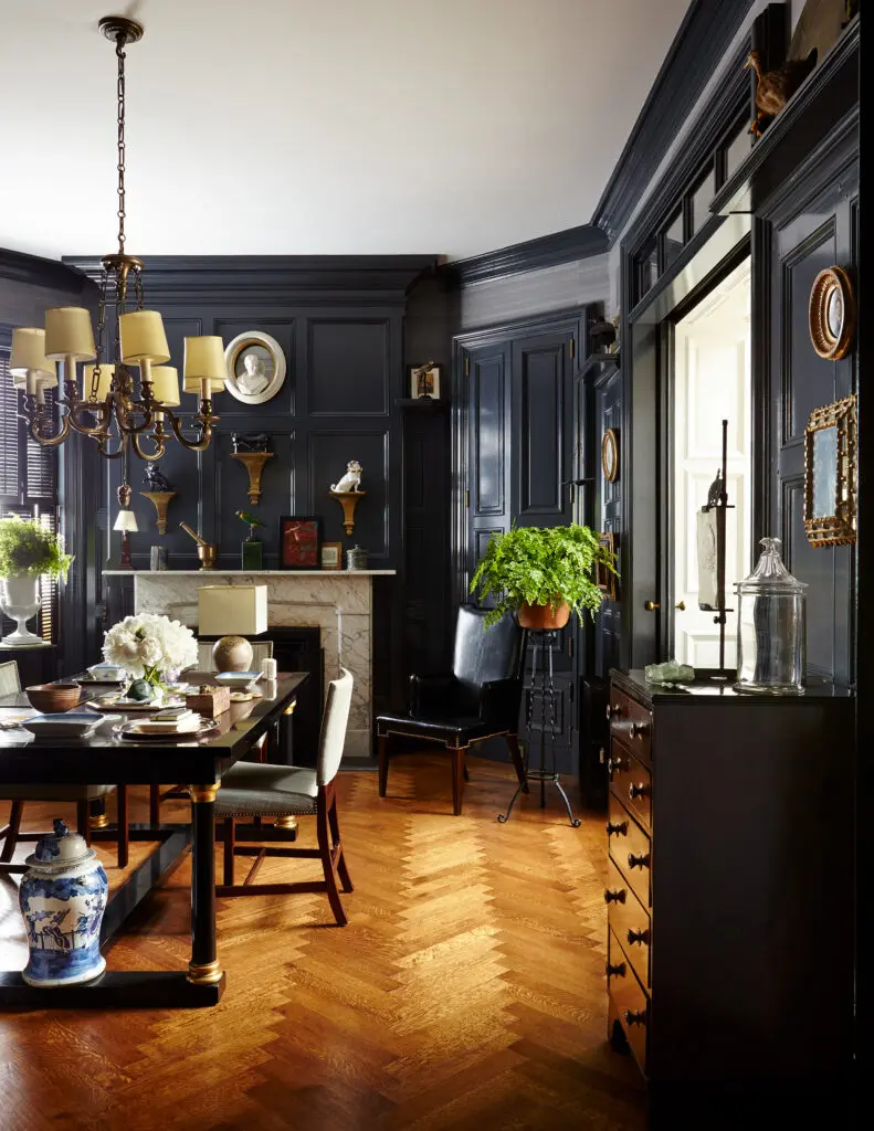 The black-lacquered, gilt and cordovan dining bureau was inspired by a Maison Jansen piece, the side chairs are Kaare Klint, and the 1920s chandelier is from a college dining hall. The herringbone floors are hand-scraped and fumed white oak. Designed by Sawyer | Berson.  (Photo by Joshua McHugh)