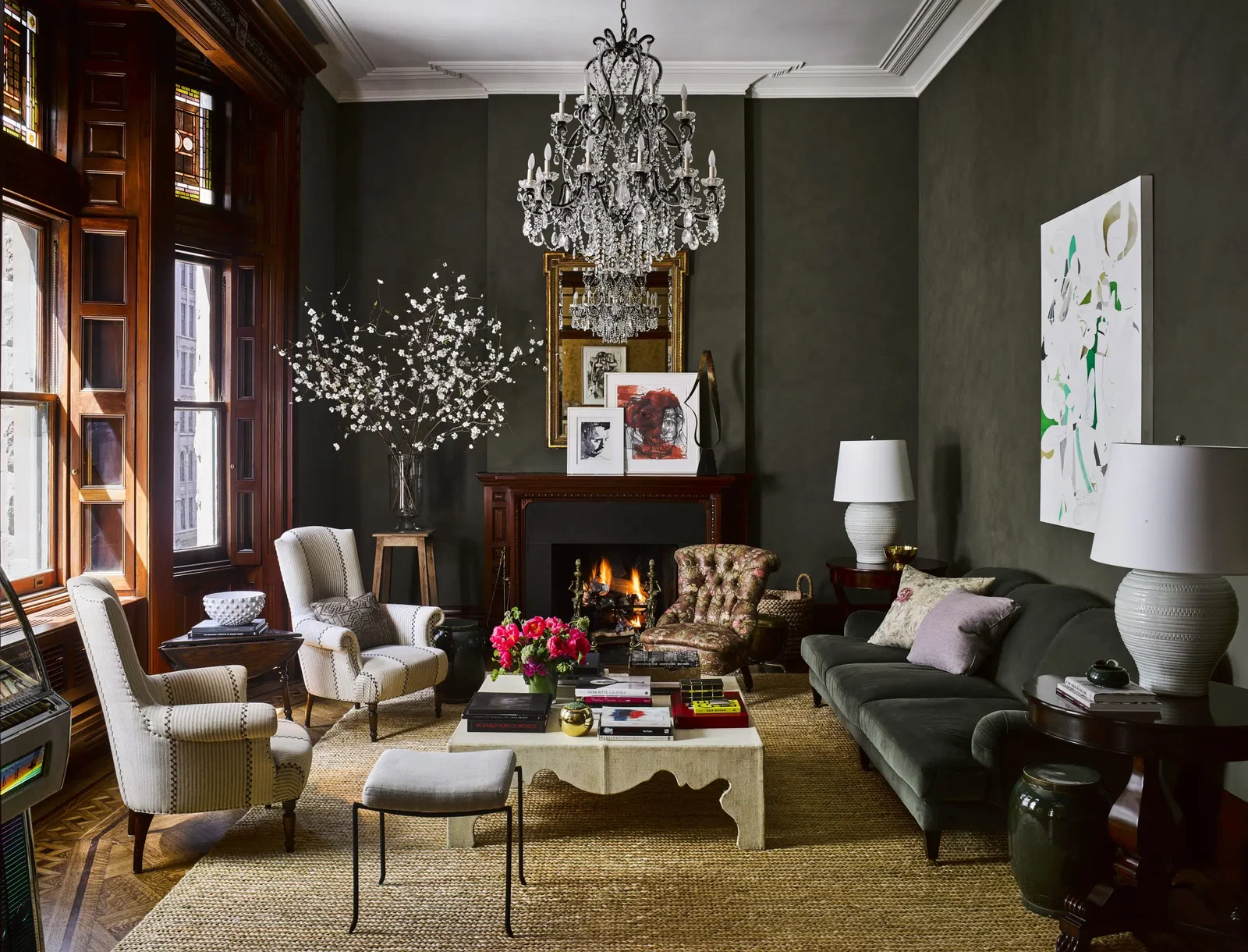 In a living room designed by Carrier and Company, deep-green-saturated walls and sofa, a neoclassical gilt mirror, and lounge chairs recall the apartment’s original period. The slipper chair belonged to Lauren Bacall. On the mantel are artworks by Thomas Libetti and George Condo. The majority of the furnishings, including furniture, fabrics, paint, lighting, and floor coverings, throughout are from Ralph Lauren Home except where noted. (Photo by Douglas Friedman)