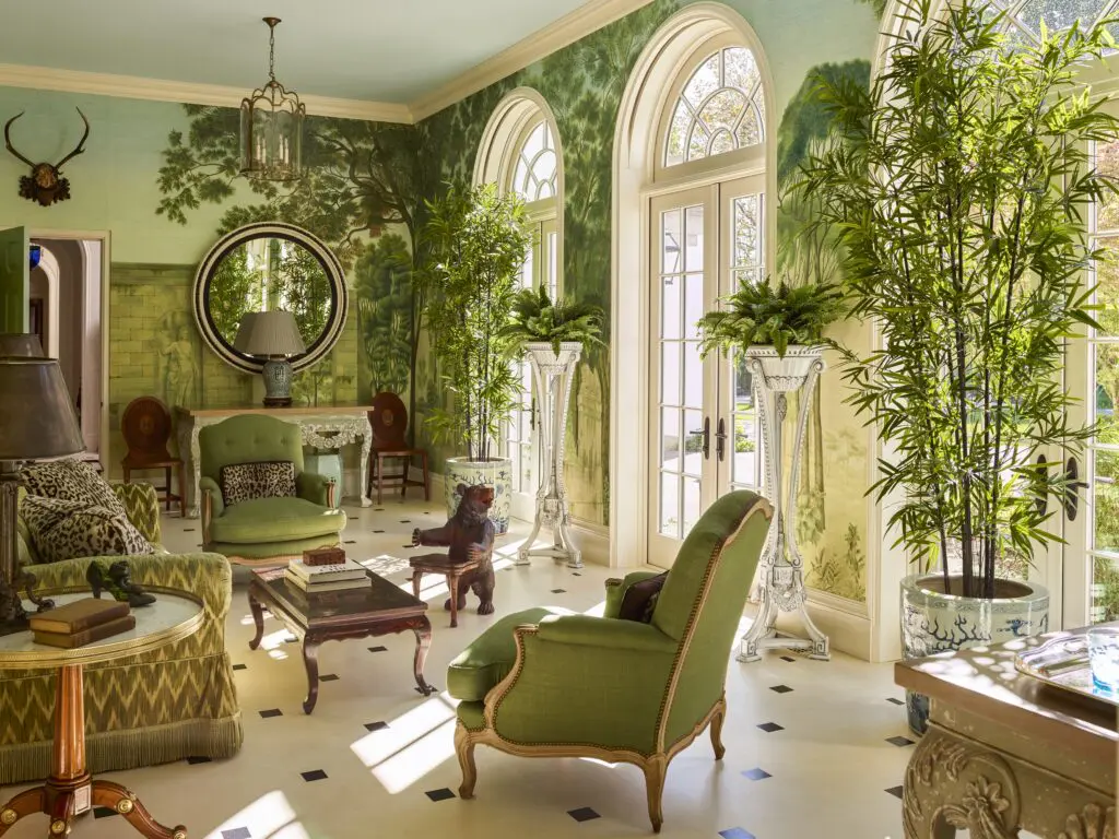 Lit by three arched French doors, a conservatory  in a house designed by architect Peter Pennoyer, has wood floors painted to simulate stone; interior design Redd Kaihoi. (Photo by Eric Piasecki)