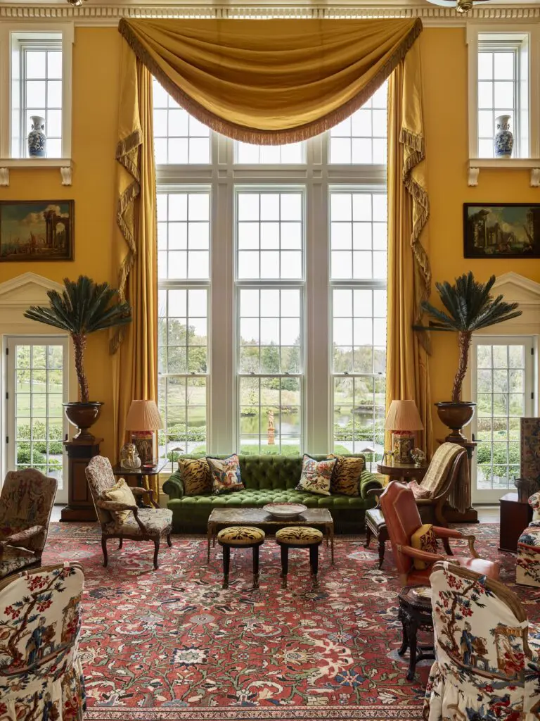 The great window in the double-height living room overlooking the pond, designed by Peter Pennoyer, is flanked by pedimented doorways and upper windows supported by brackets. (Photo by Eric Piasecki)