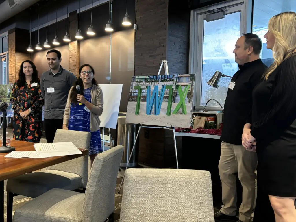 The artist trio, Michelle Old, Stacy Moore and Kevin Giuseppetti, present their "TWTX" creation with the underwriters, Chris and Jenny Elmi. (Photo by Laura Landsbaum)