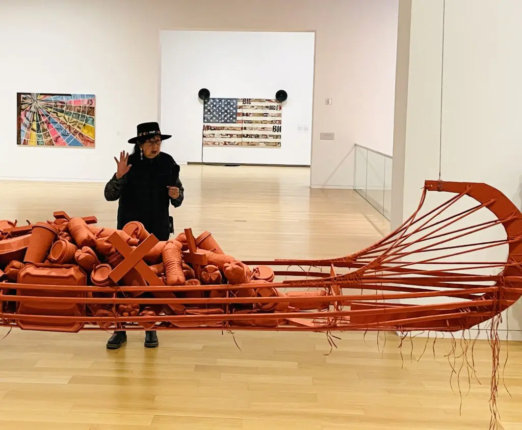 The artist explains the meaning of the red ochre colored canoe sculpture. (Photo by Courtney Dabney)
