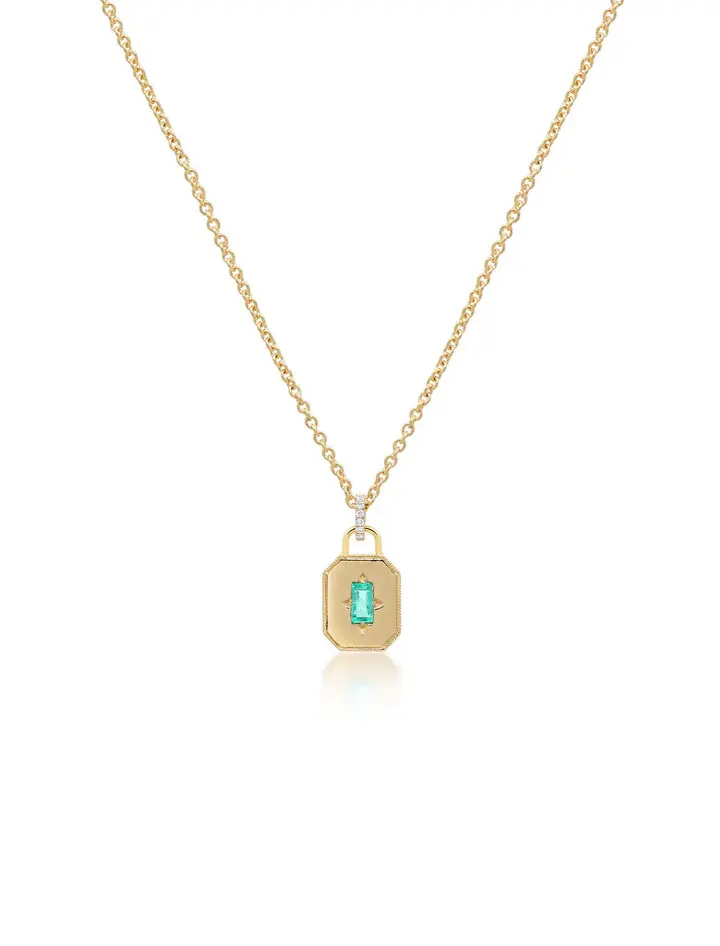 This State Property Spade Warisan Minor Emerald Necklace features an adjustable 18K yellow gold chain and an octagonal charm set with a bright green baguette emerald at its center. 