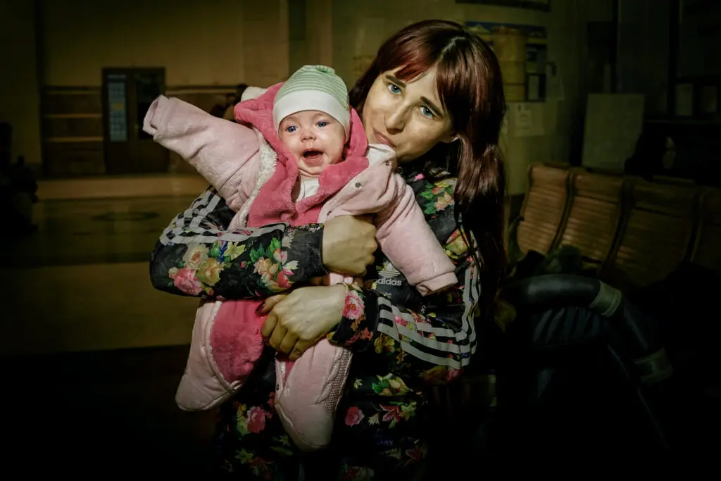 Alena Grom's "Eva," 2022. Marina, 26, fled the bombing in Kharkiv with her grandmother and two daughters. Her 1-year-old daughter, Eva, is constantly fussy. It is difficult to prepare milk formula and bottle-feed an infant while on the run. The family first arrived in Uzhgorod, Ukraine, and then left the country. (Courtesy Ukrainian Association of Professional Photographers)