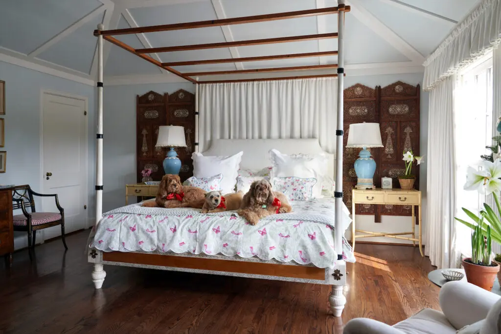 In the main bedroom, dogs Lilibet, Queenie, and India Jane lounge on Porthault linens. Antique Indian bed from John Rosselli & Associates. Moroccan screens. (Photo by Pär Bengtsson)