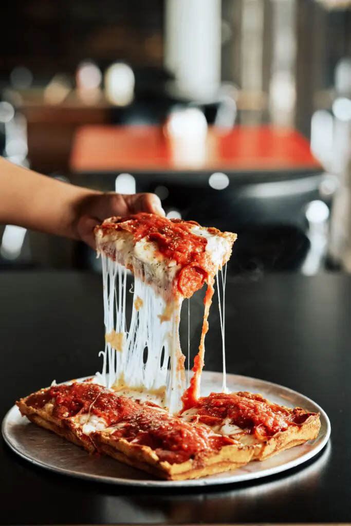 A cheesy pull on a slice of Via 313's pizzas shows plenty. Known for its rectangular shape, each is baked in a heavy steel pan (inspired by the auto parts trays found in the motor city in the 1940s (Photo courtesy Champion Management)
