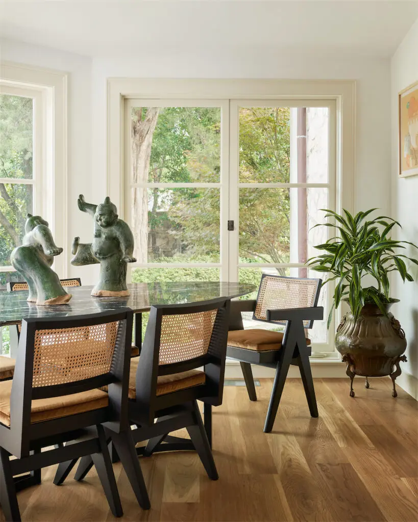 An unused space was turned into a breakfast room with custom green marble table, Cassina chairs from Scott + Cooner. Vintage Buddhas from Brendan Bass. (Photo by Stephen Karlisch)