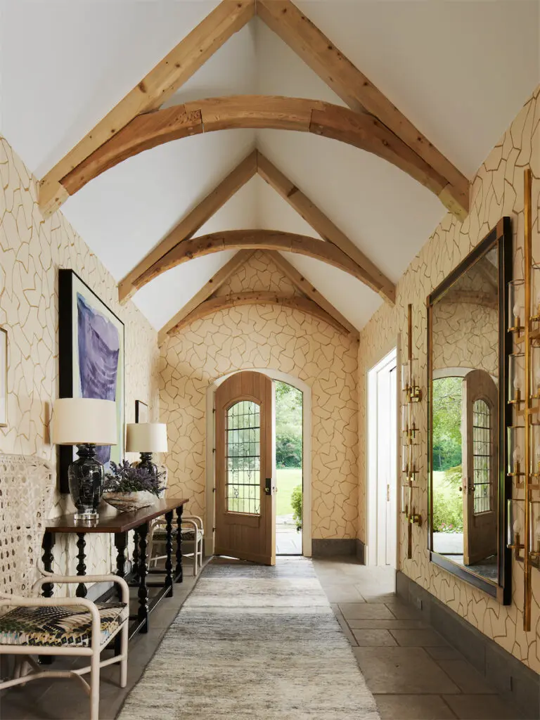 The vaulted entry was a later addition to the house, with a vintage door, console, and McGuire chairs. Custom Paul Schneider lamps. Wallpaper by Donghia. (Photo by Stephen Karlisch)