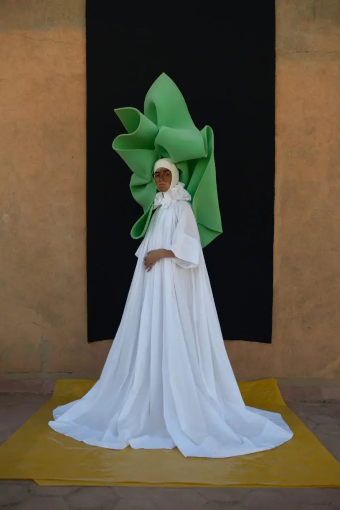 Model in a white caftan with green
headdress by @artsimous, 2021. (Courtesy @artsimous 2021)