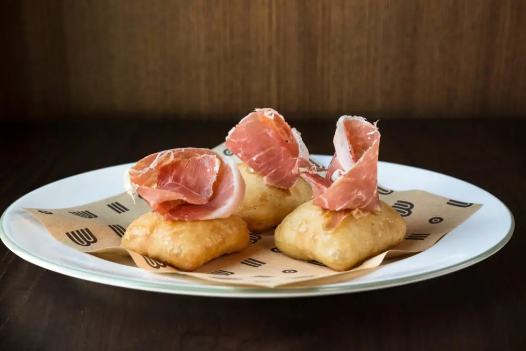 Fluffy, savory ricotta filled beignets ($19) are topped with thin slices of Lady Edison country ham at Bar Bludorn. (Photo by Caroline Fontenot)
