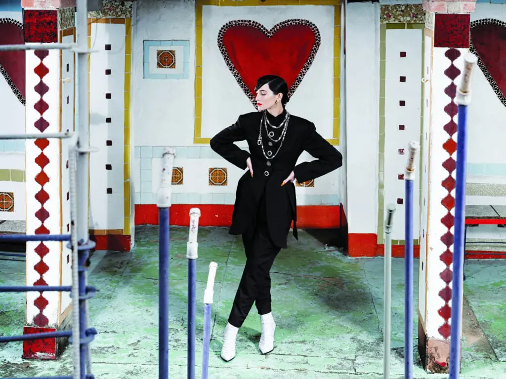 Louis Vuitton jewel-button frock jacket $6,050, fitted high-waist carrot pant $2,390. LV Knot ankle boot, Louisette earrings $450, and LV Prestige necklaces $1,480 to 3,450. 