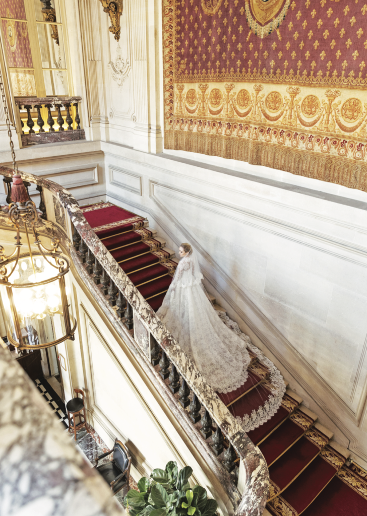 Bride Maggie Phillips walks up a grand staircase at the Cercle de l’Union Interalliée. (Photo by John Cain Photography)