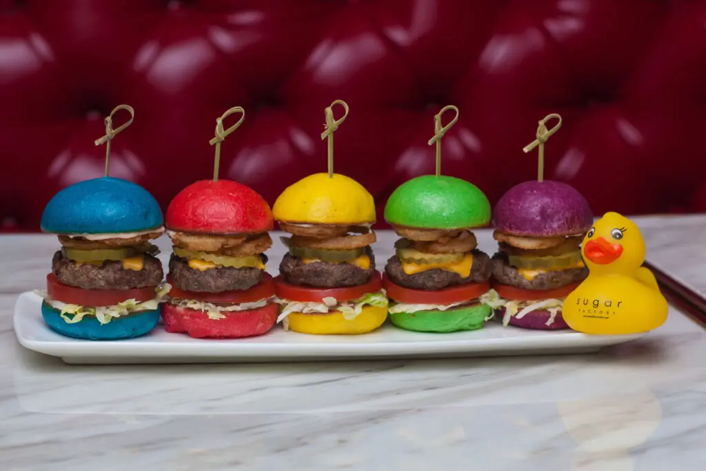 The Sugar Factory menu features appetizers like fried mac and cheese pops and the Sugar Factory’s rainbow sliders, a colorful twist on the American classic poised on diminutive buns colored every hue in the rainbow.
