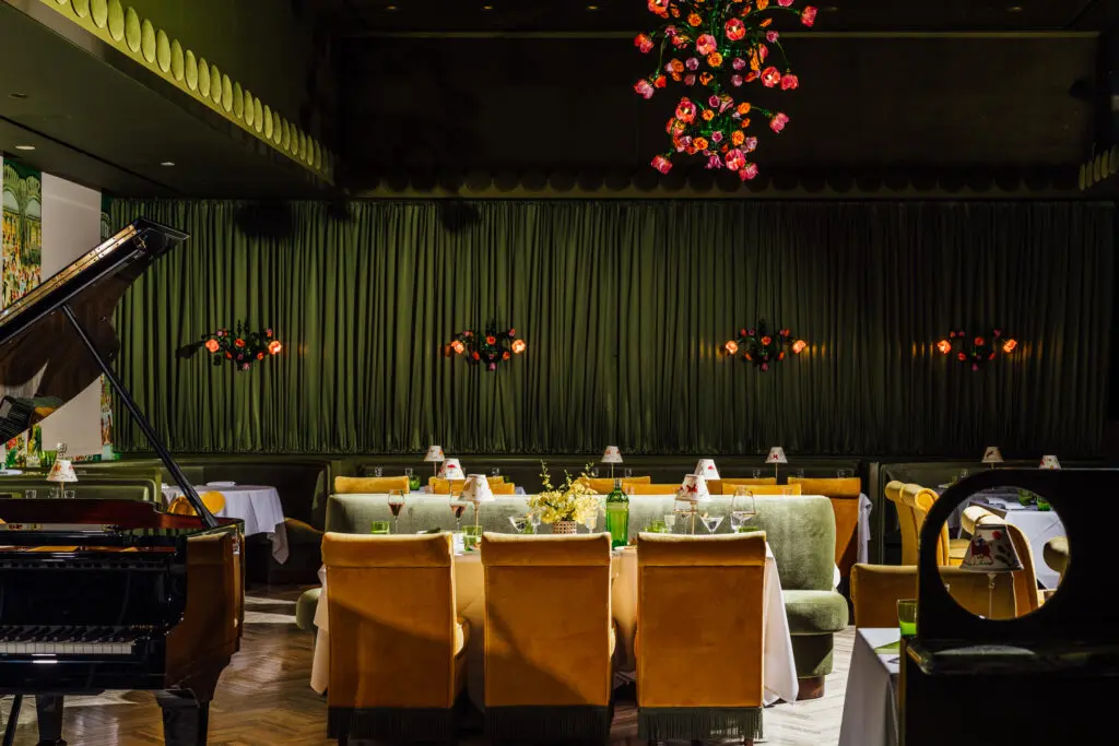 Designed in part by the Texas-based architecture group FoxFox Studios, the Marigold Club's intimate dining room is appointed with plush moss and marigold-colored velvet upholstery replete with bouillon fringe cosseting each diner’s seat in comfort.  (Photo by Arturo Olmos)