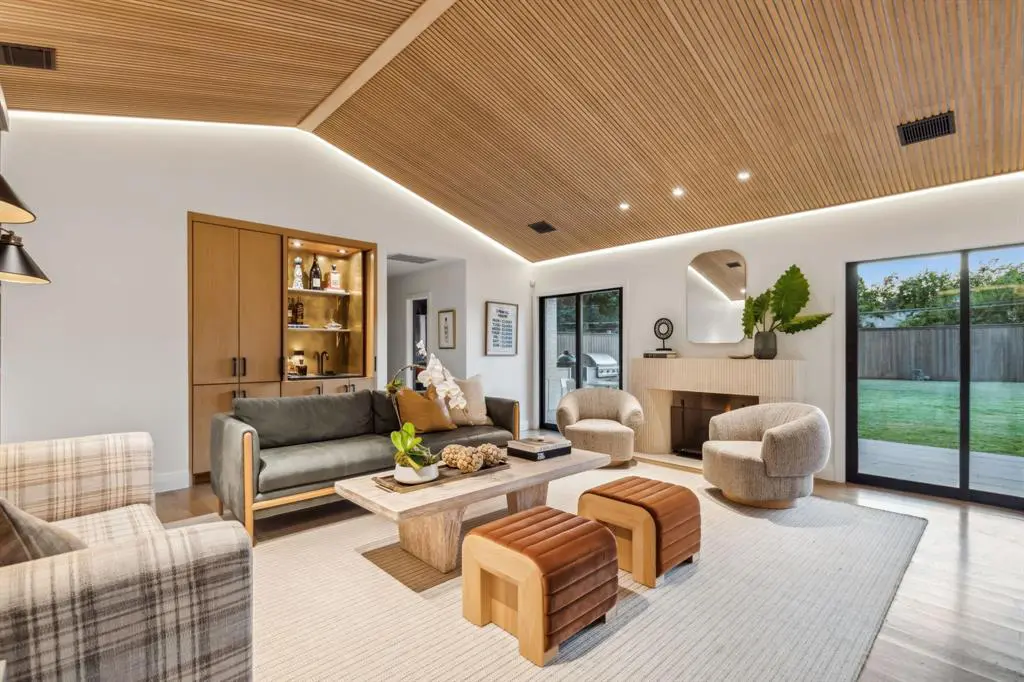 A pivot door entry and art wall opens to the living room which features vaulted wood ceilings, a custom fireplace, and a wet bar.